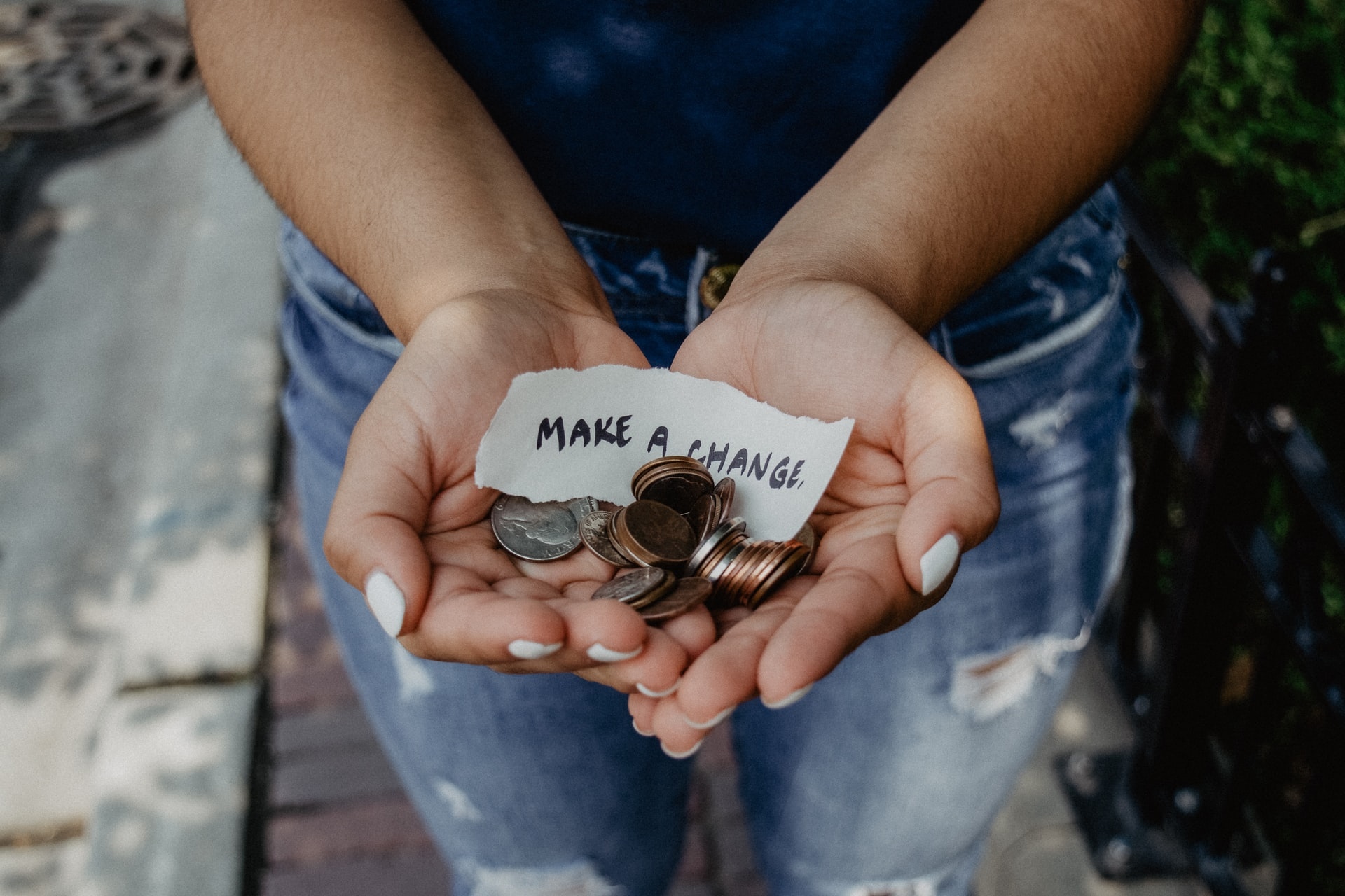 Person Holding coins and a piece of paper with Make a change written on it