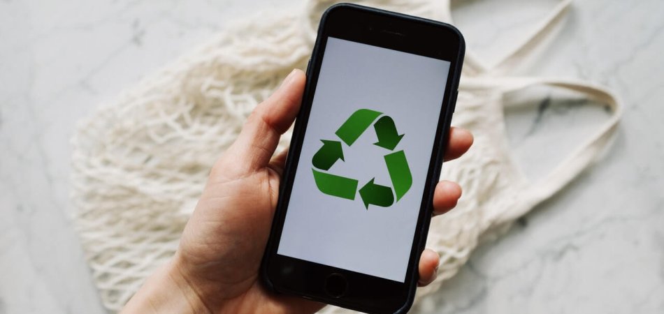 Person holding a phone showing a recycling symbol displayed on screen